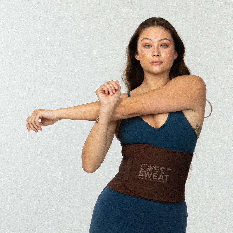 Woman stretching while wearing Sweet Sweat® Toned waist trimmer.