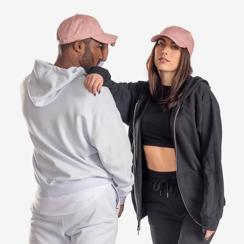 Man and woman wearing rose version of the Sweet Sweat® Classic Logo caps.