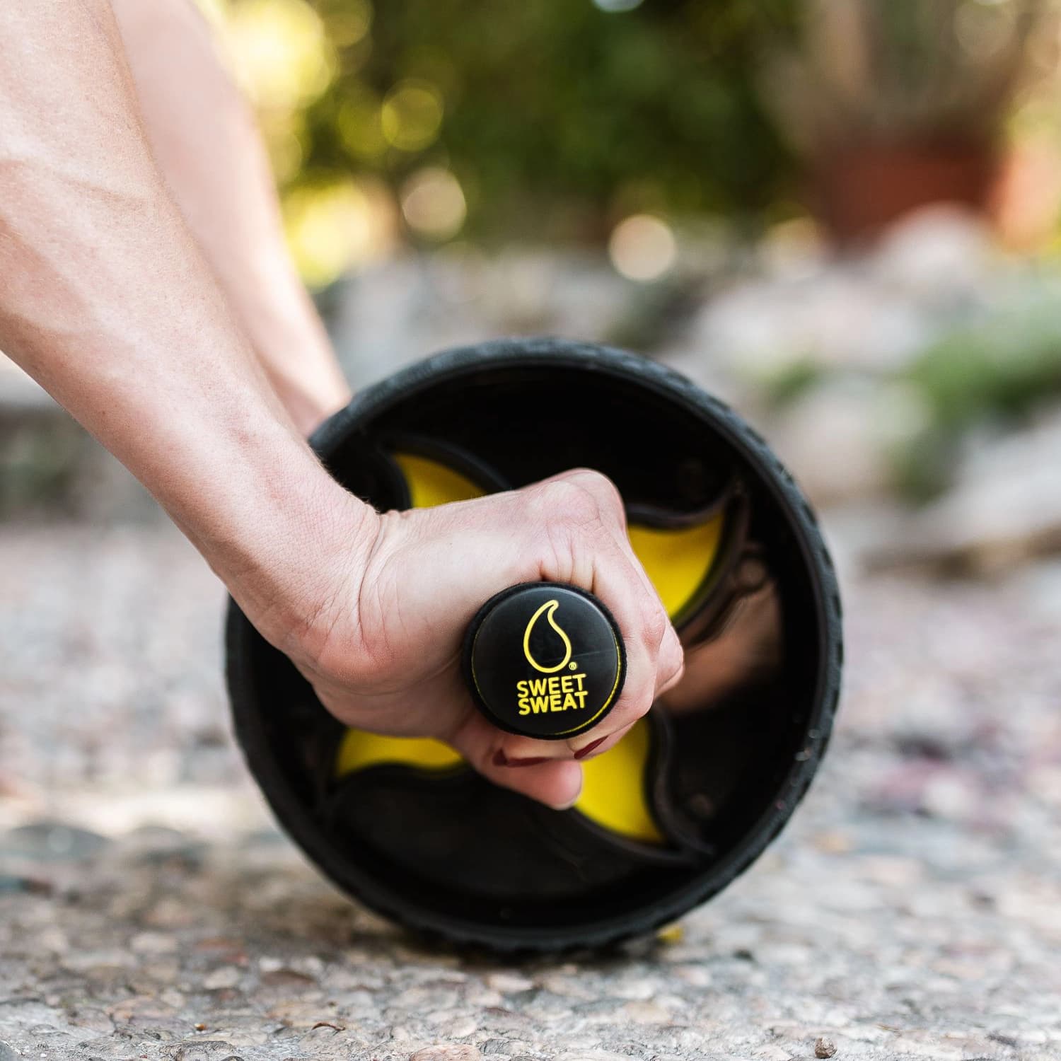 Person using Sweet Sweat® Ab Wheel outdoors.