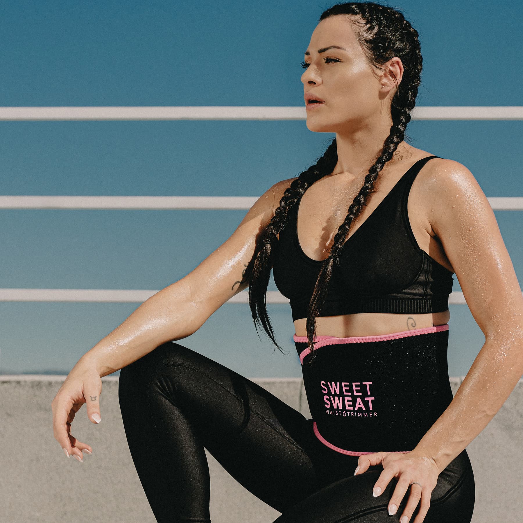 Woman in workout attire wearing a Sweet Sweat® waist trimmer.