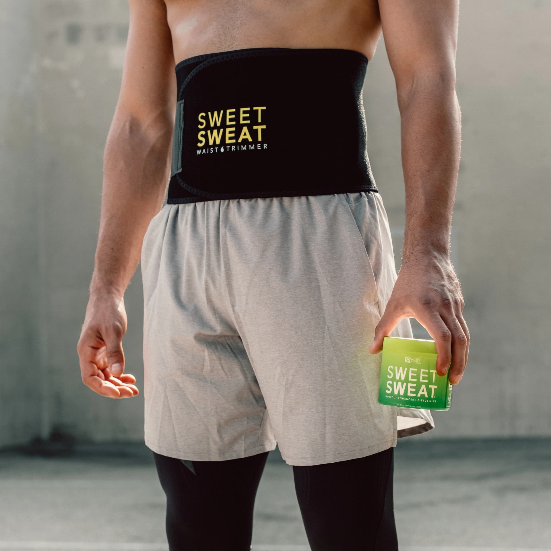 a man in a black tank top holding a green bag.