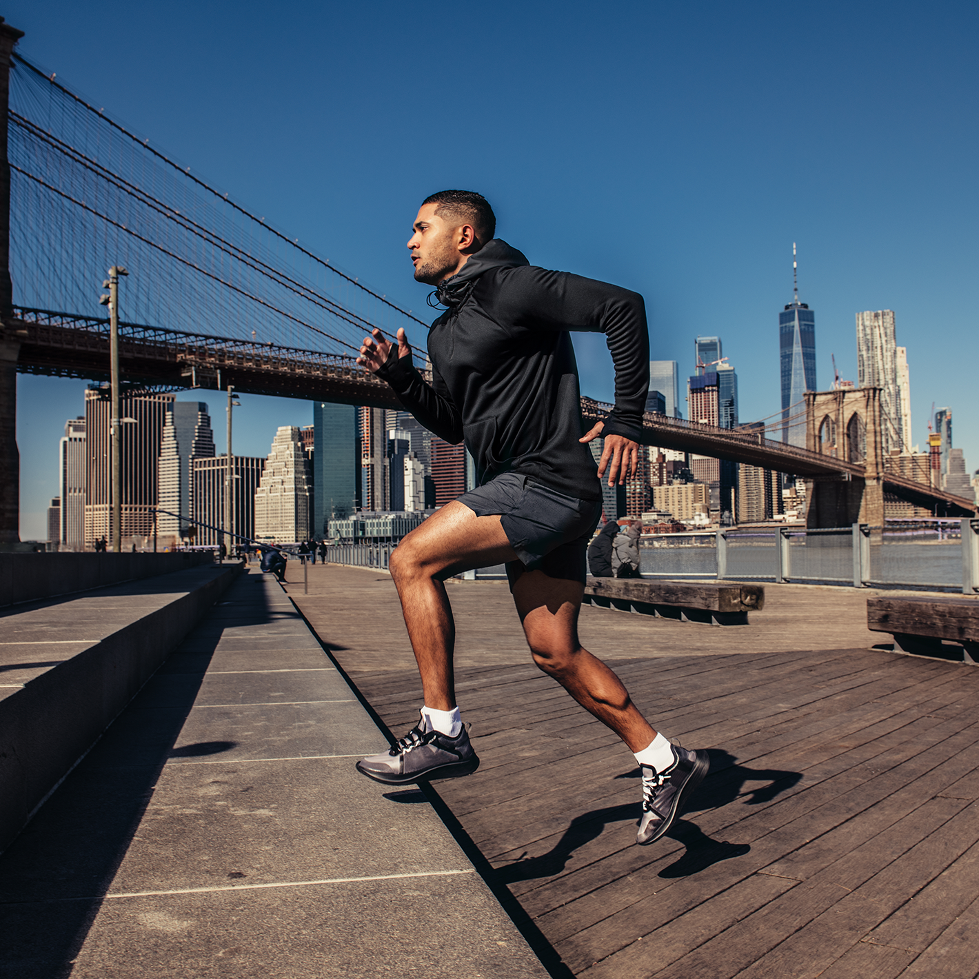 A man running on some stairs with the New York City skyline in the background.