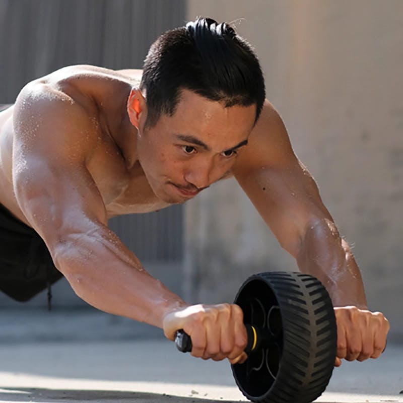 Man using Sweet Sweat® Ab Wheel to workout outdoors.