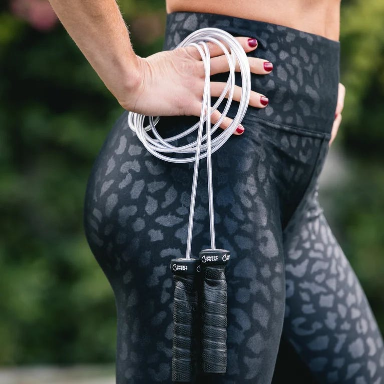 Woman holding Sweet Sweat® Light Weight Jump Rope, while hands are on her hips.