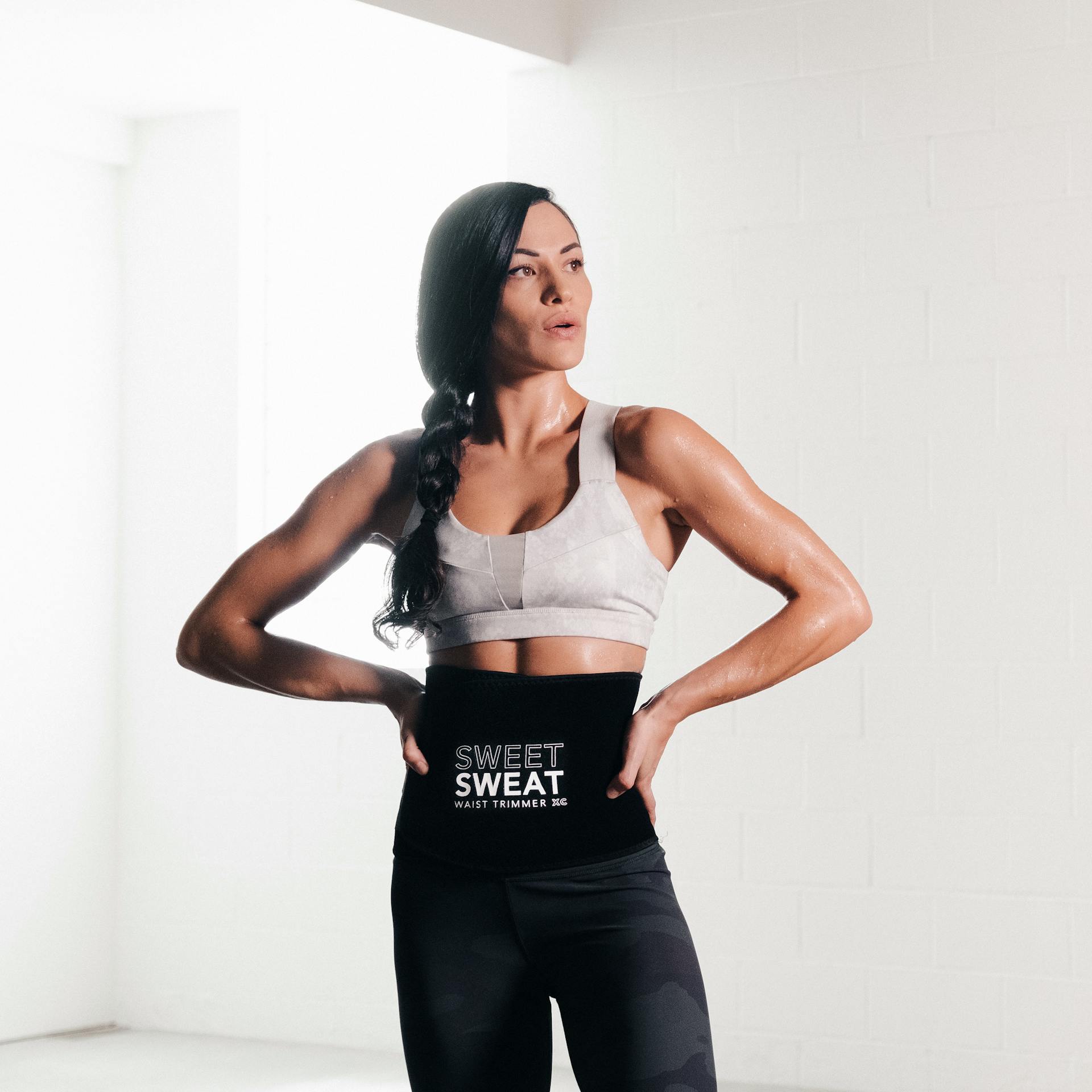 Woman in workout attire, wearing a Sweet Sweat® Xtra Coverage waist trimmer.